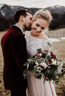 Brautpaar beim Pärchen-Fotoshooting bei einer Winterhochzeit im Boho-Stil, Braut trägt selbstgemachte Ohrringe und einen wunderschönen Winter-Brautstrauss
