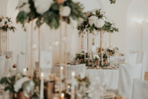 Elegante und pompöse Hochzeitsdekoration. Elegante hohe Centerpieces mit vielen Kerzen und vielen Blumen in den Farben kupfer weiß grün
